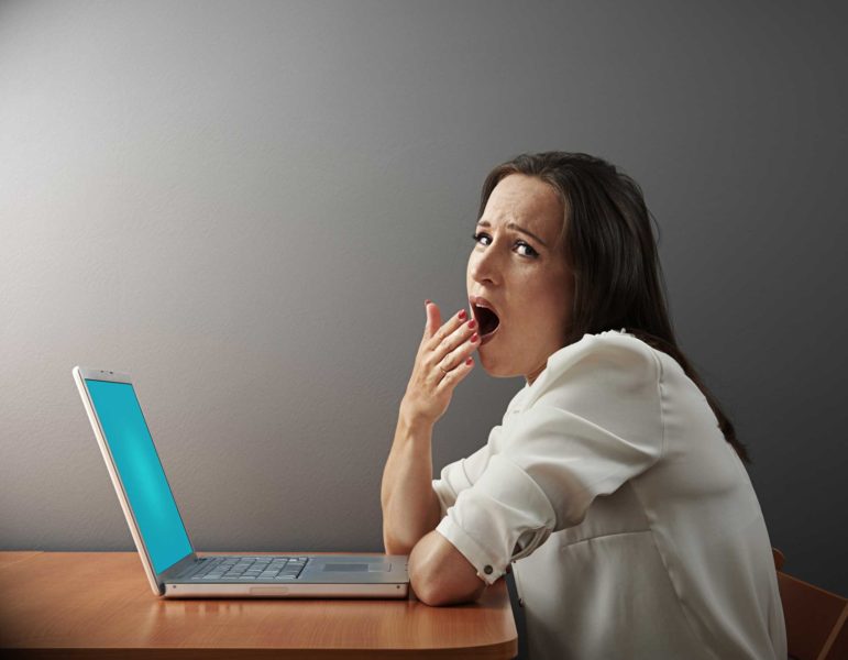 Woman yawning with open laptop