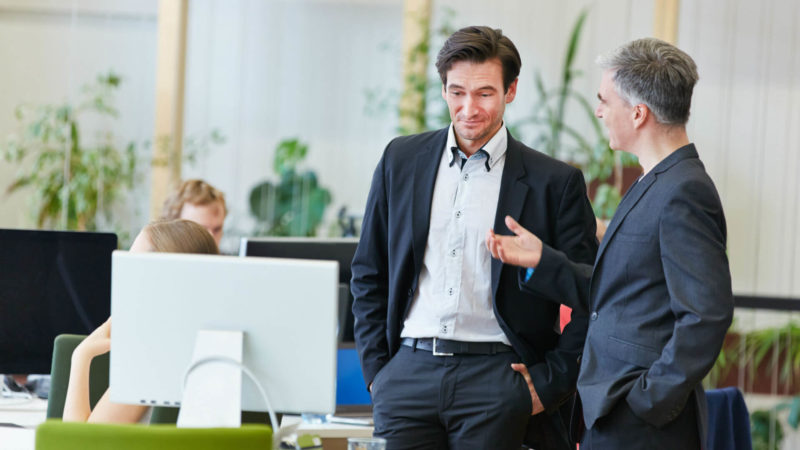 Two men chatting in front of PC