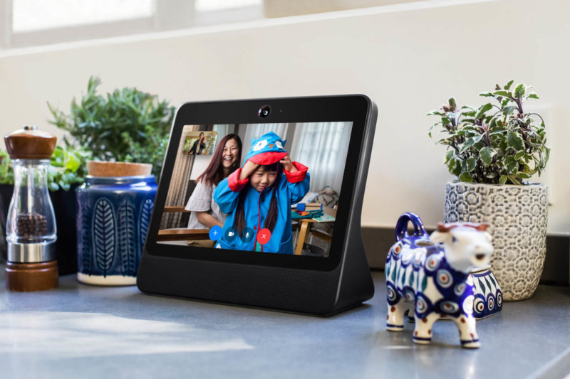 A Facebook Portal device site on a home countertop next to salt and pepper shakers and indoor plants.