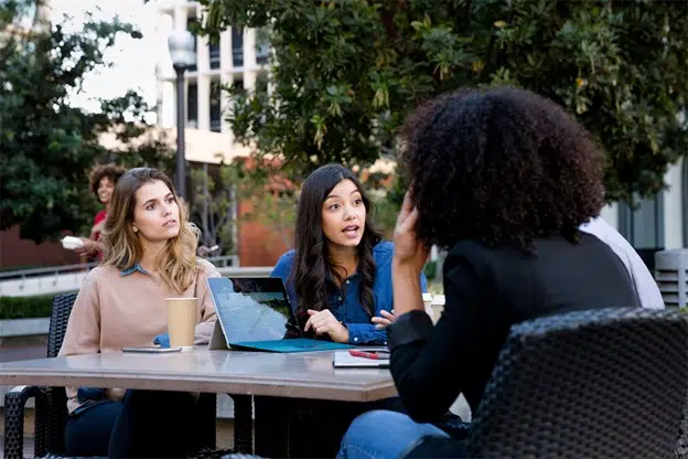 Three women at a table looking at a tablet computer