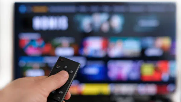 Man-holding-remote-control-with-TV-in-the-background