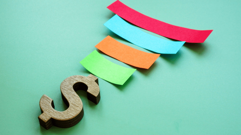 Paper strips form a revenue funnel and a dollar sign