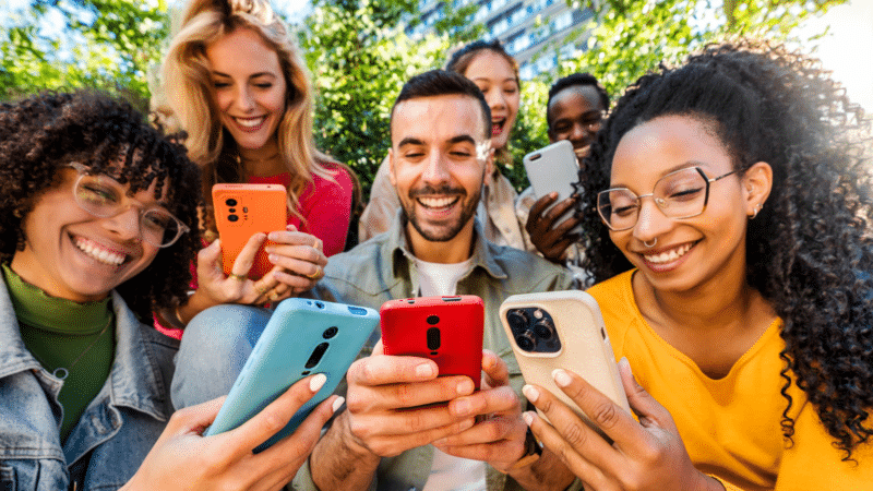 Group of young people using smart mobile phone outdoors