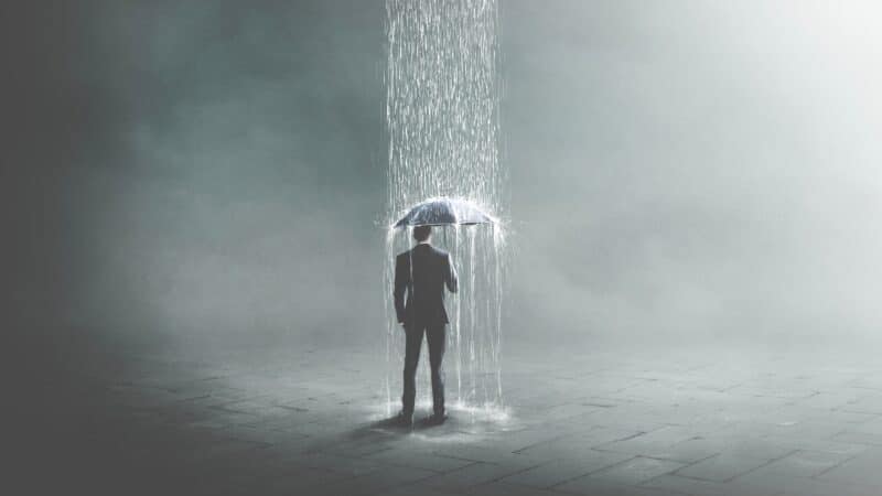 Businessman hiding from rain