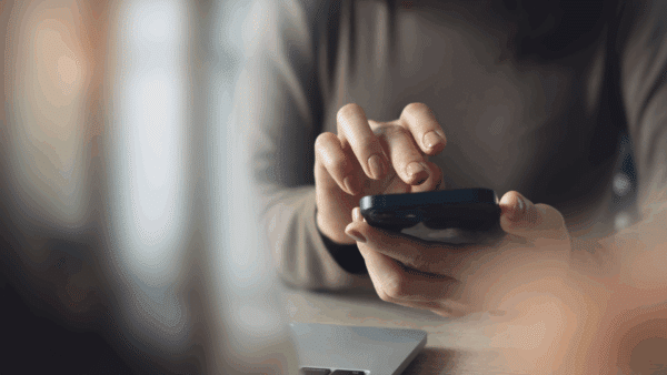 Business-woman-using-mobile-phone-with-laptop-computer-on-office-table