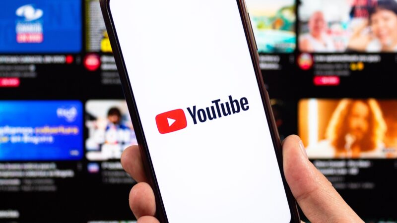 YouTube logo on smartphone with blurred interface at background