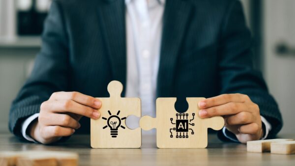 A-businessman-holding-a-jigsaw-puzzle-with-a-light-bulb-and-AI-connected